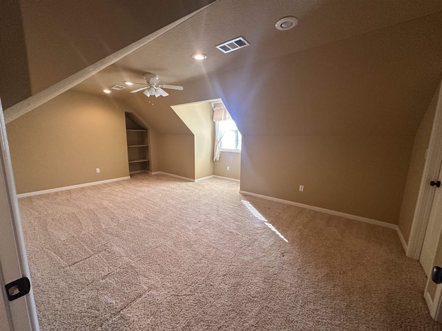 additional living space featuring ceiling fan, lofted ceiling, carpet flooring, and a textured ceiling