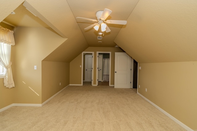 additional living space with vaulted ceiling, light colored carpet, and ceiling fan