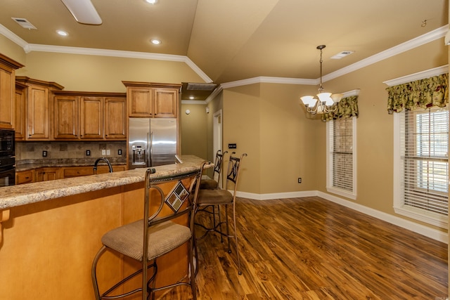 kitchen featuring crown molding, lofted ceiling, a kitchen bar, and black appliances