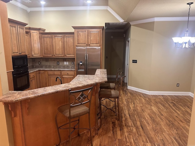 kitchen featuring crown molding, dark hardwood / wood-style flooring, a kitchen breakfast bar, and black appliances