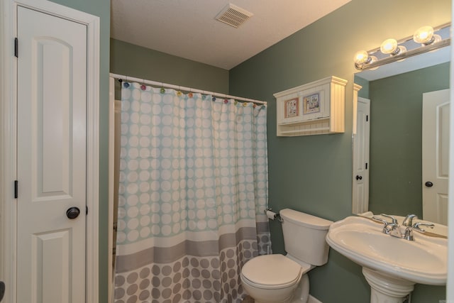 bathroom featuring a shower with curtain, toilet, sink, and a textured ceiling