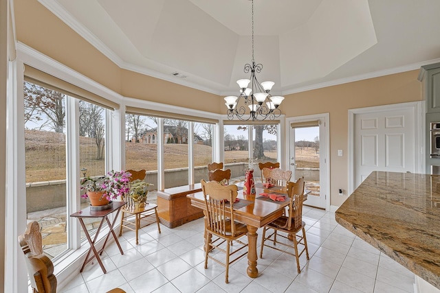 tiled dining area with a tray ceiling, ornamental molding, and a chandelier