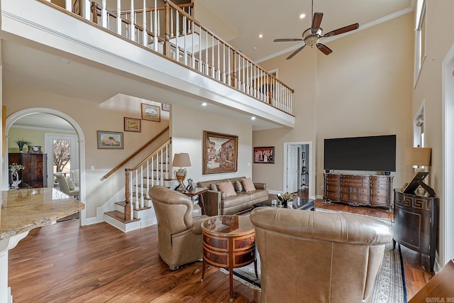 living room featuring hardwood / wood-style flooring, ceiling fan, crown molding, and a high ceiling