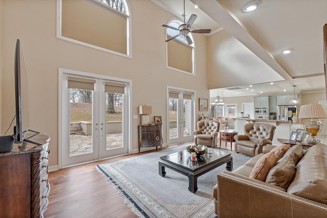 living room with a towering ceiling, french doors, ceiling fan, ornamental molding, and hardwood / wood-style flooring