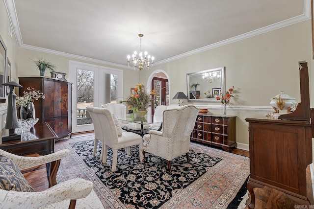 dining space with crown molding, wood-type flooring, french doors, and an inviting chandelier