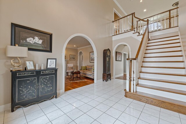 tiled entryway featuring a high ceiling and crown molding