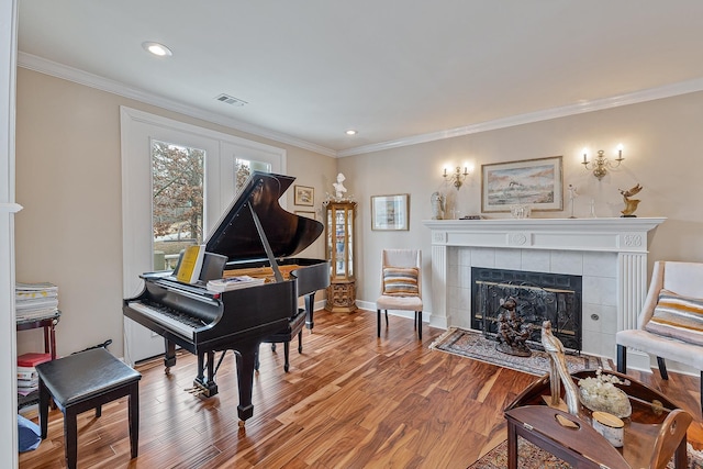 miscellaneous room featuring a tile fireplace, crown molding, and hardwood / wood-style floors