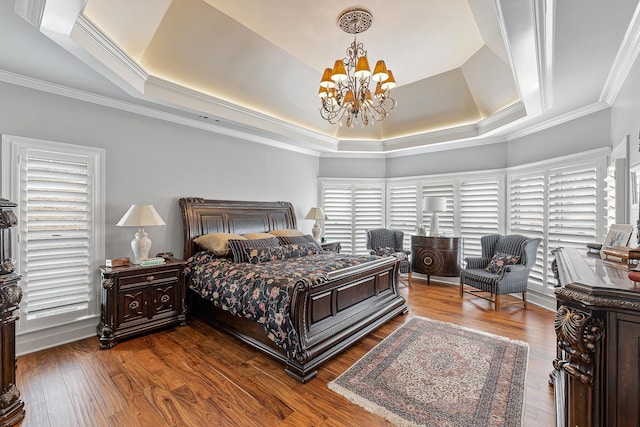 bedroom with a tray ceiling, dark hardwood / wood-style floors, ornamental molding, and an inviting chandelier