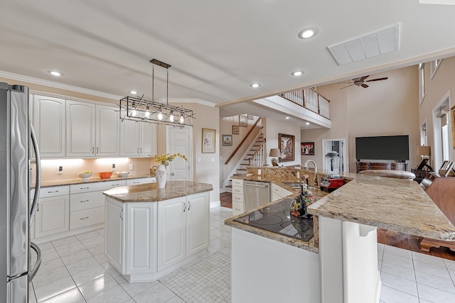 kitchen with white cabinets, appliances with stainless steel finishes, sink, hanging light fixtures, and a kitchen island with sink