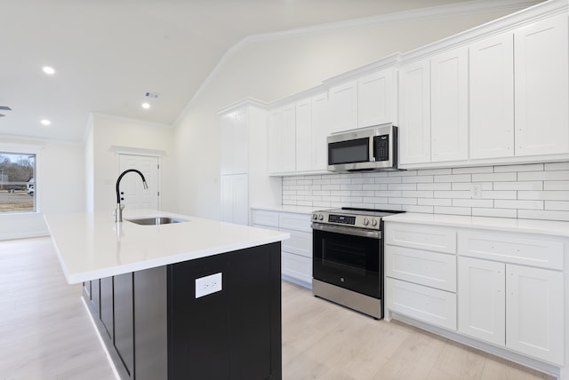 kitchen featuring vaulted ceiling, stainless steel appliances, white cabinets, and an island with sink