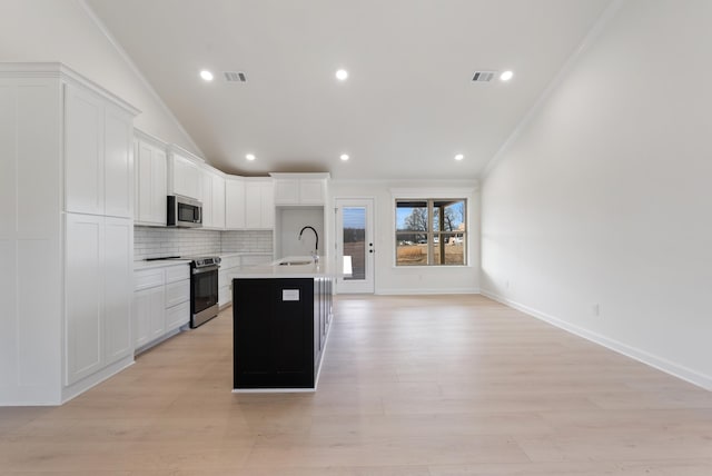 kitchen with sink, an island with sink, stainless steel appliances, and white cabinetry