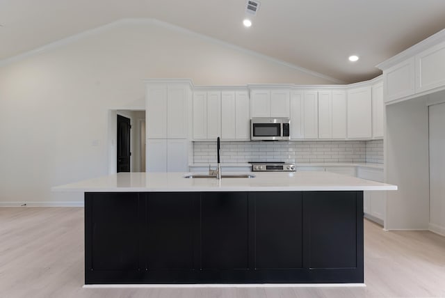 kitchen featuring white cabinets, stainless steel appliances, an island with sink, decorative backsplash, and sink