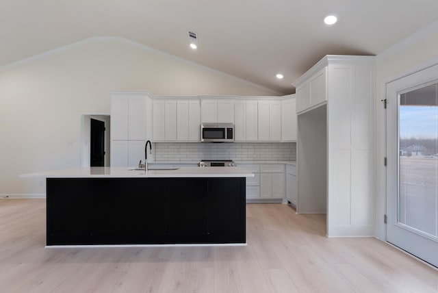 kitchen with a center island with sink, white cabinetry, backsplash, and sink