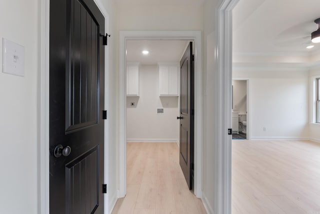 hall with ornamental molding and light hardwood / wood-style floors