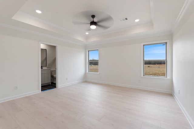 unfurnished room featuring a raised ceiling, ceiling fan, ornamental molding, and light hardwood / wood-style floors