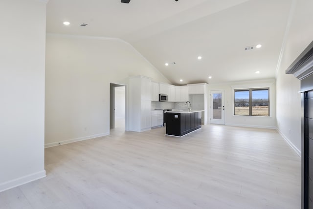 kitchen featuring tasteful backsplash, light hardwood / wood-style floors, sink, a kitchen island with sink, and white cabinets