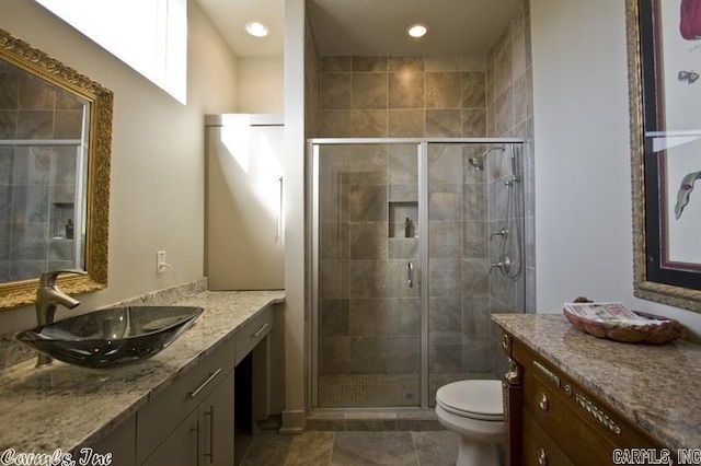 bathroom with toilet, vanity, tile patterned floors, and a shower with door