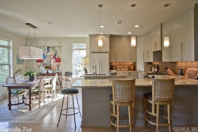 kitchen with decorative light fixtures, plenty of natural light, a kitchen breakfast bar, and decorative backsplash