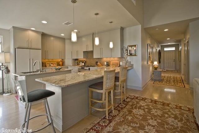 kitchen with built in fridge, a kitchen breakfast bar, pendant lighting, and stainless steel stove