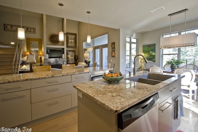 kitchen with dishwasher, pendant lighting, a wealth of natural light, sink, and a kitchen island with sink