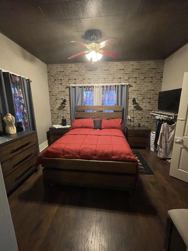 bedroom featuring ceiling fan, brick wall, and hardwood / wood-style flooring