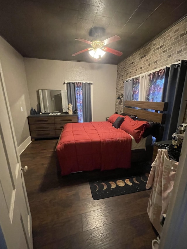 bedroom with ceiling fan, dark wood-type flooring, and brick wall