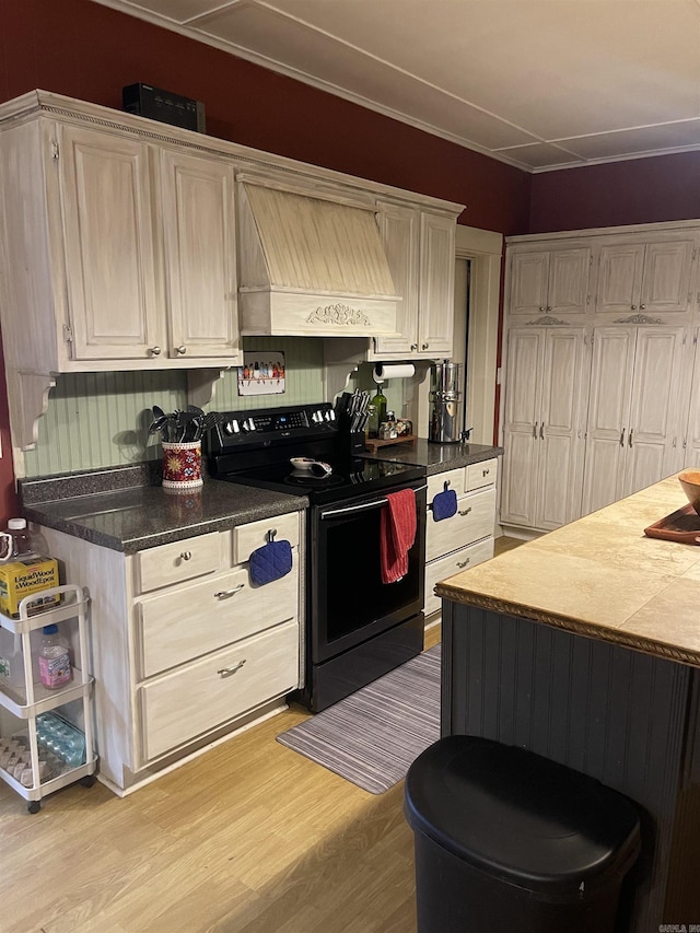 kitchen featuring premium range hood, light wood-type flooring, and black range with electric cooktop