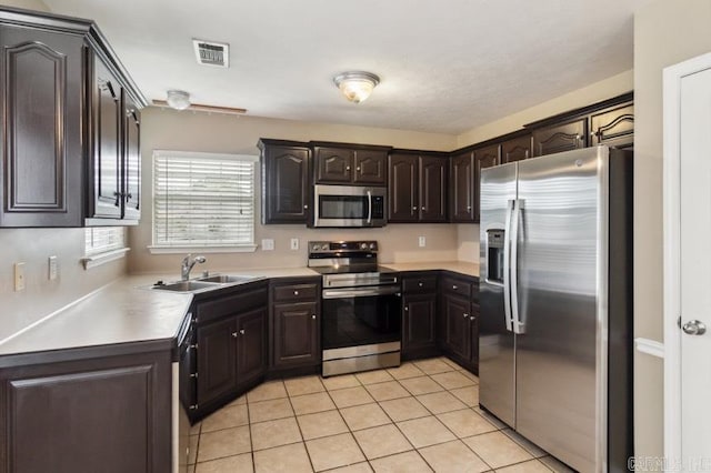 kitchen featuring light tile patterned floors, appliances with stainless steel finishes, dark brown cabinetry, and sink