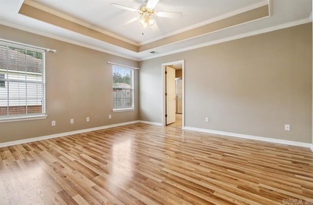 unfurnished room featuring a wealth of natural light, crown molding, light hardwood / wood-style floors, and a tray ceiling