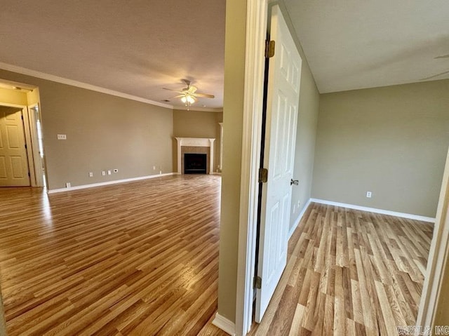 unfurnished living room featuring ceiling fan, crown molding, and light hardwood / wood-style floors