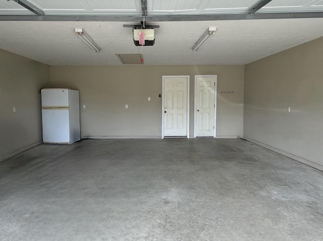 garage featuring white fridge and a garage door opener