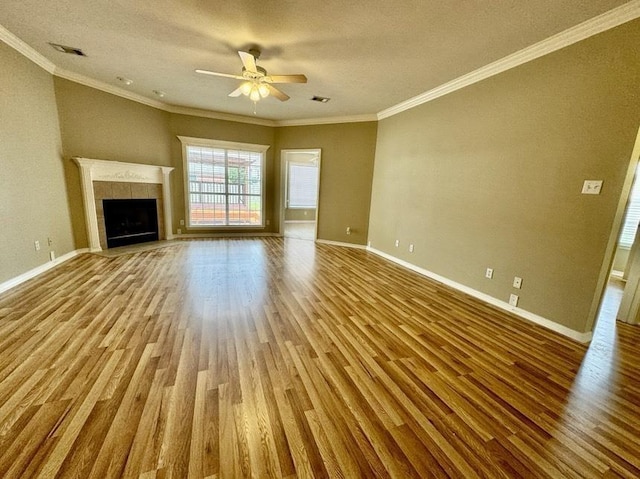 unfurnished living room with ceiling fan, a tile fireplace, crown molding, and light hardwood / wood-style flooring