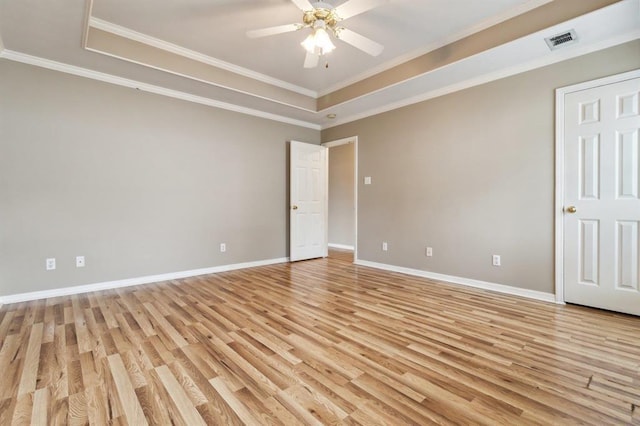 unfurnished room with ceiling fan, crown molding, a raised ceiling, and light wood-type flooring