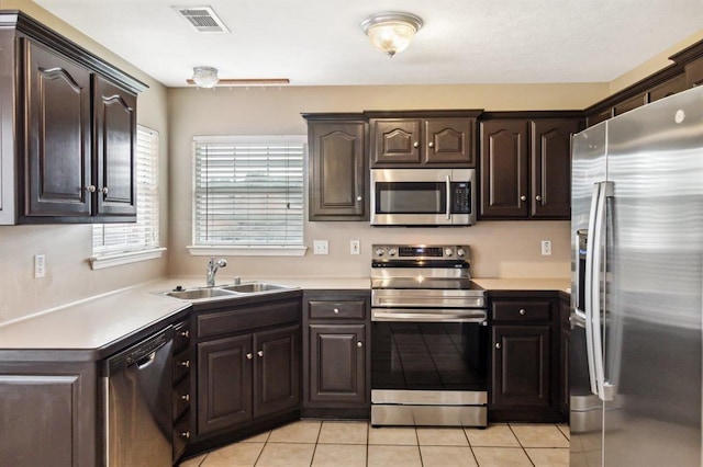 kitchen featuring light tile patterned flooring, appliances with stainless steel finishes, dark brown cabinets, and sink