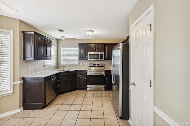 kitchen with light tile patterned floors, dark brown cabinets, sink, and stainless steel appliances