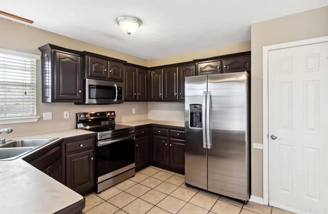 kitchen featuring light tile patterned floors, stainless steel appliances, dark brown cabinets, and sink