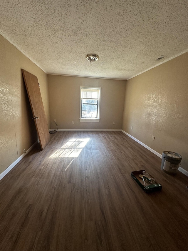 spare room featuring a textured ceiling and dark hardwood / wood-style floors