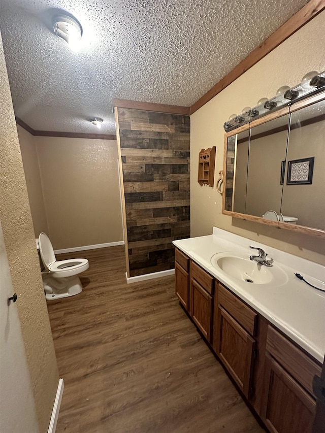 bathroom featuring hardwood / wood-style flooring, a textured ceiling, vanity, and ornamental molding