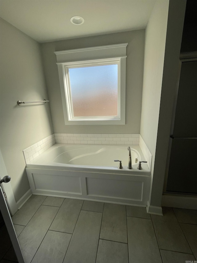 bathroom with tile patterned floors and a tub