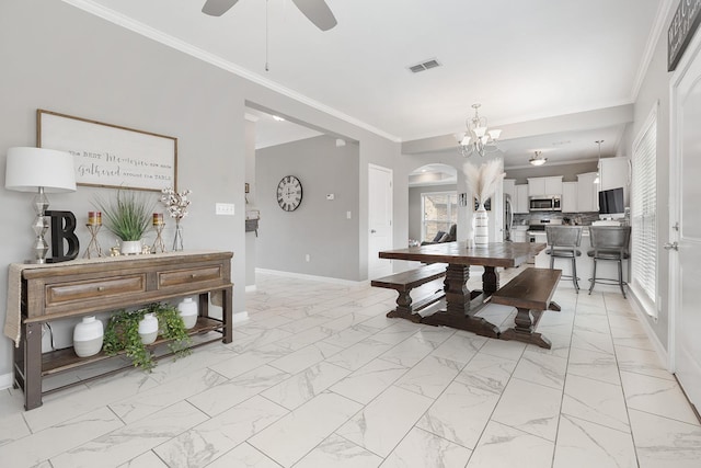 dining area with crown molding and ceiling fan with notable chandelier