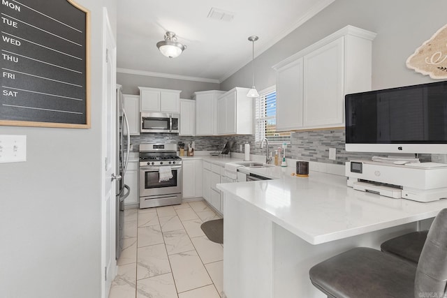 kitchen featuring white cabinetry, appliances with stainless steel finishes, a kitchen breakfast bar, pendant lighting, and sink