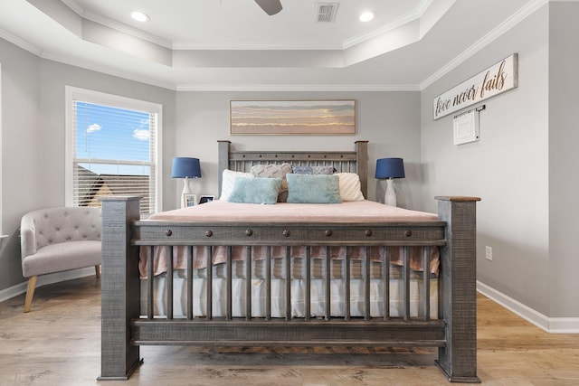 bedroom with ceiling fan, hardwood / wood-style floors, a tray ceiling, and crown molding