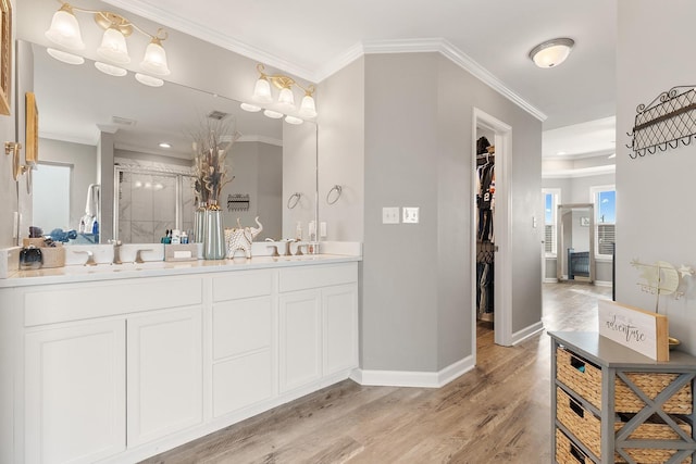 bathroom with vanity, wood-type flooring, a shower with door, and ornamental molding