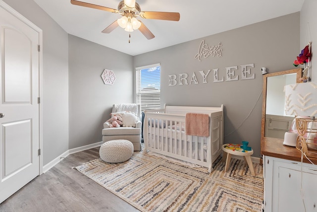 bedroom with ceiling fan, light hardwood / wood-style floors, and a crib