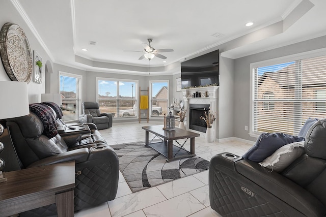 living room featuring ceiling fan, crown molding, a raised ceiling, and a fireplace