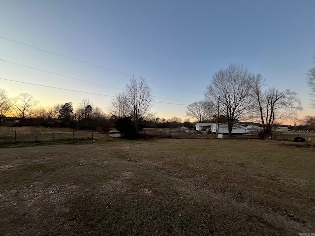 yard at dusk featuring a rural view