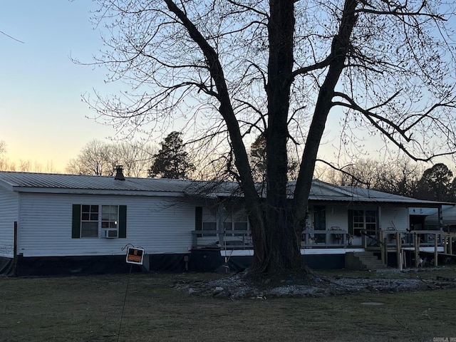 back house at dusk with cooling unit and a lawn