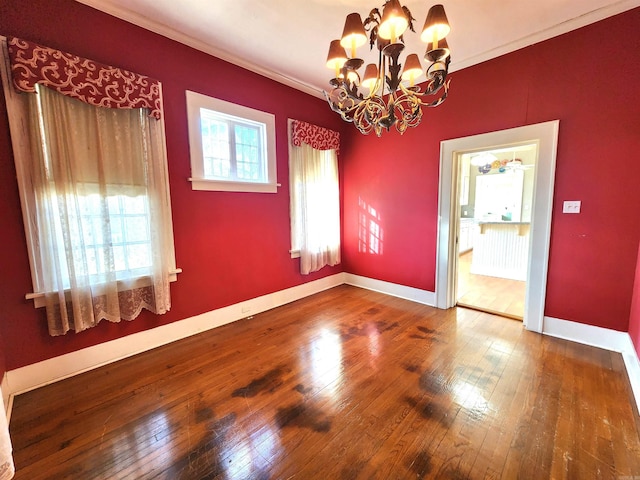 empty room with ornamental molding, hardwood / wood-style flooring, and a notable chandelier