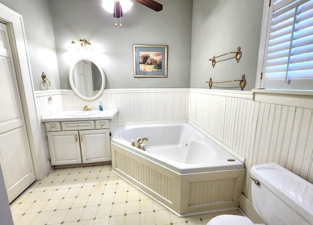 bathroom featuring toilet, vanity, a tub, and ceiling fan