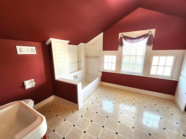 bathroom featuring vaulted ceiling, a bathing tub, toilet, and sink